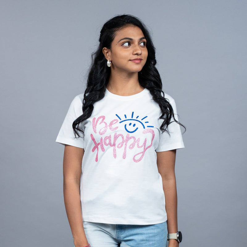 Woman wearing Be Happy tee styled with denim shorts—casual weekend mood
