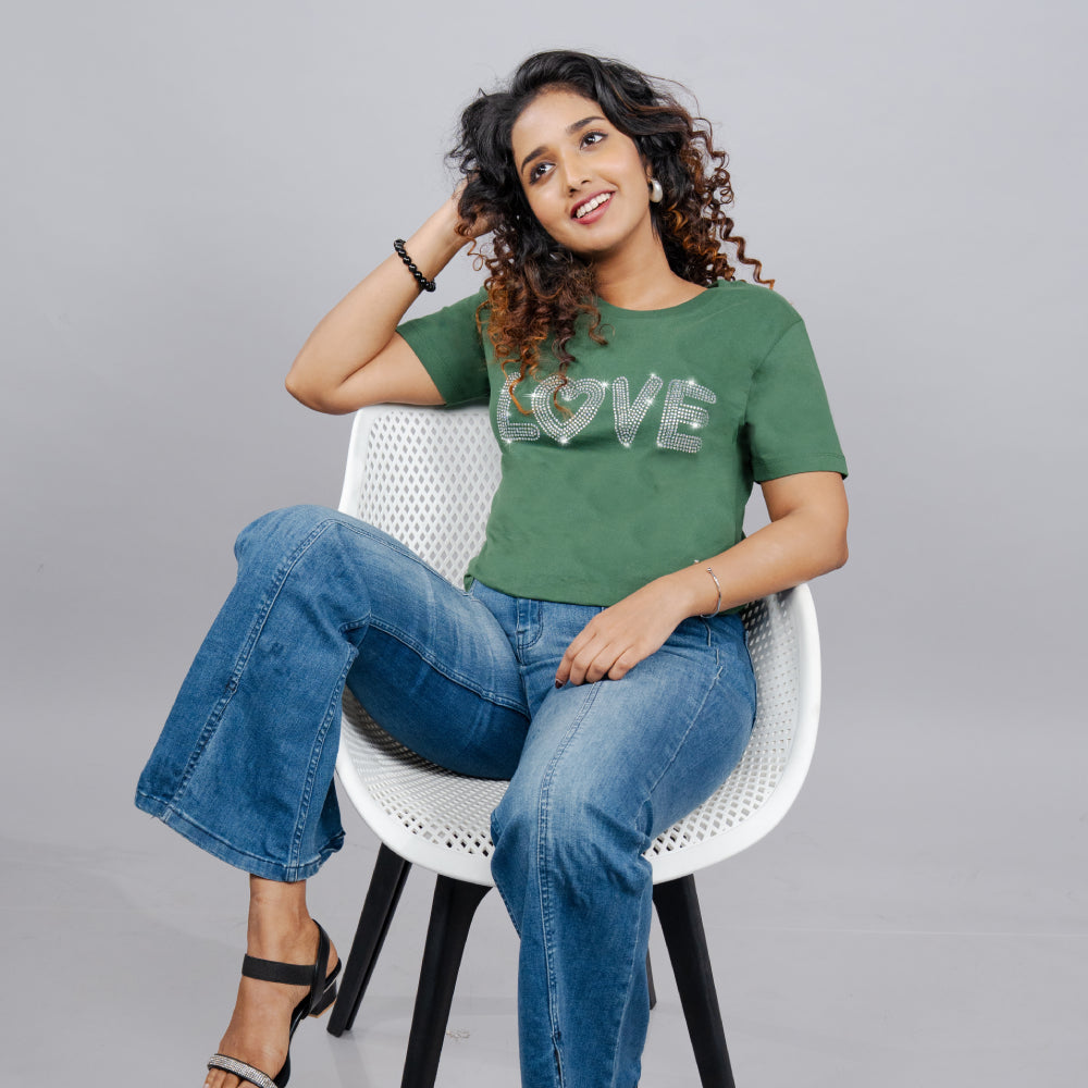 Close-up of bottle-green tee highlighting glitter-stone “Love” lettering and heart motif