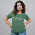 Woman wearing bottle-green “Love” tee paired with jeans—casual-glam energy