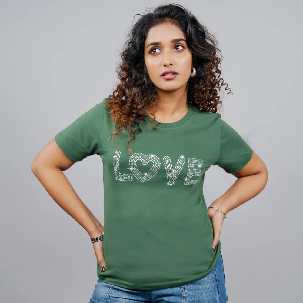 Woman wearing bottle-green “Love” tee paired with jeans—casual-glam energy