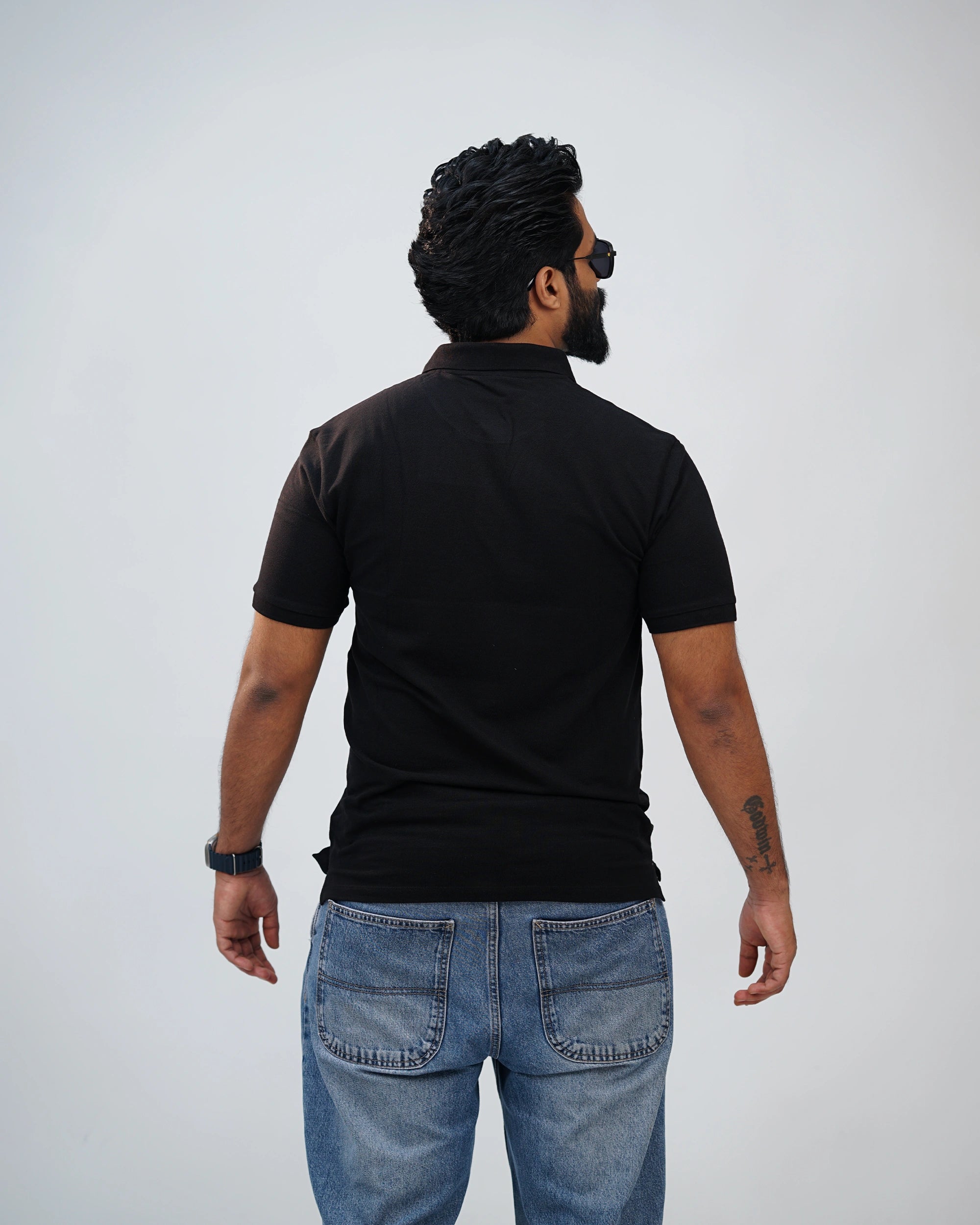 Back view of black polo tee showcasing clean silhouette and understated style