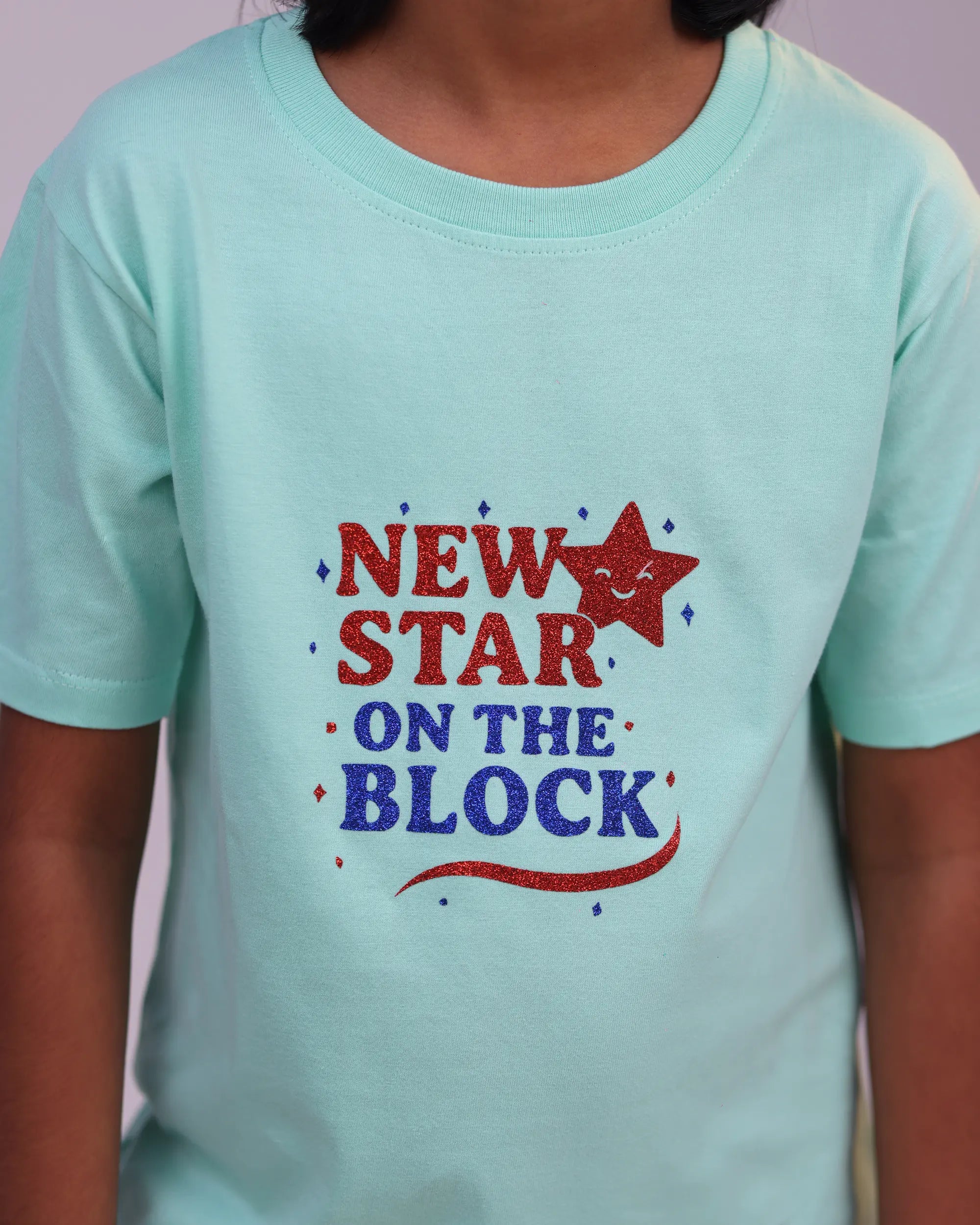 Kid wearing “New Star” tee joyfully—mint mood meets youthful confidence