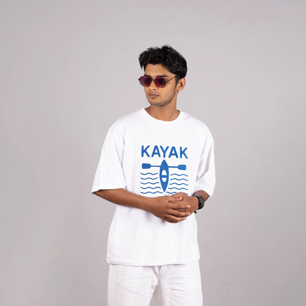 Man wearing the white “Kayak” tee styled with casual shorts—bold design meets laid-back ease