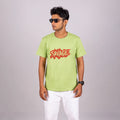 Man wearing kiwi green “Savage” tee with casual trousers—bold style with playful edge