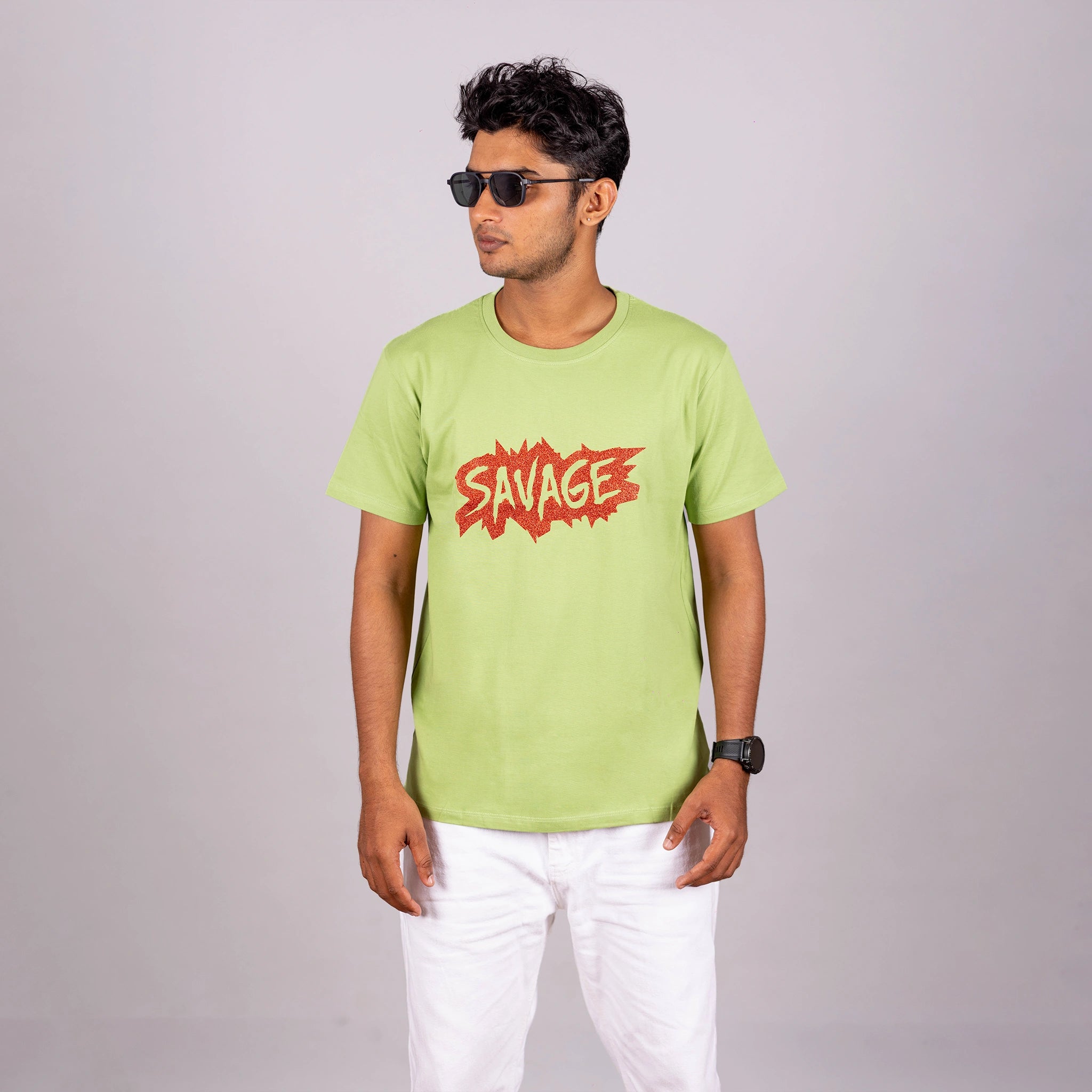 Man wearing kiwi green “Savage” tee with casual trousers—bold style with playful edge