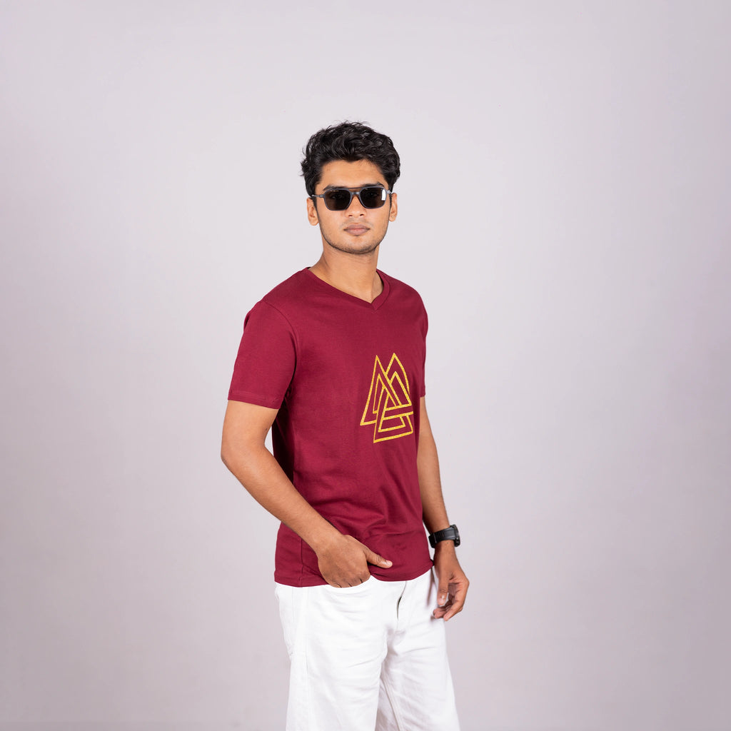 Man wearing maroon tee with gold triangle print—sharp, modern edge in everyday style