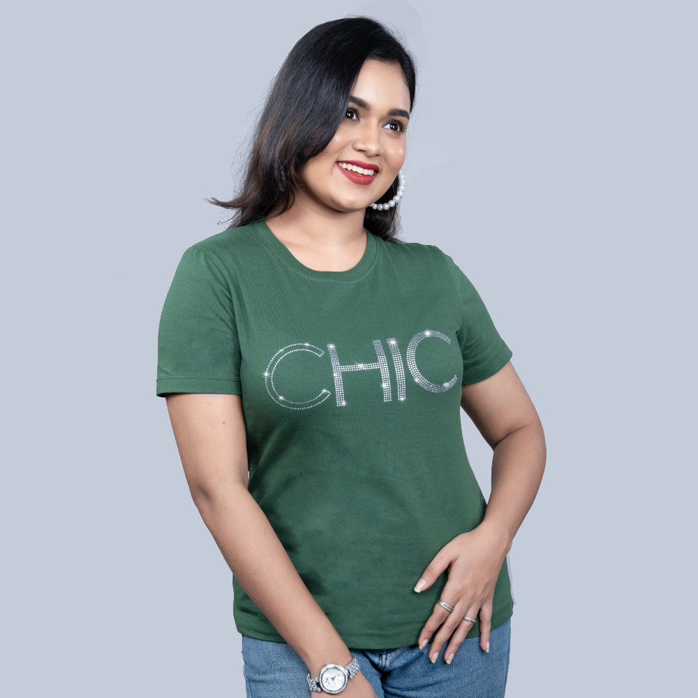Woman wearing olive-green "Chic" tee with rhinestone lettering, styled with denim — refined cool