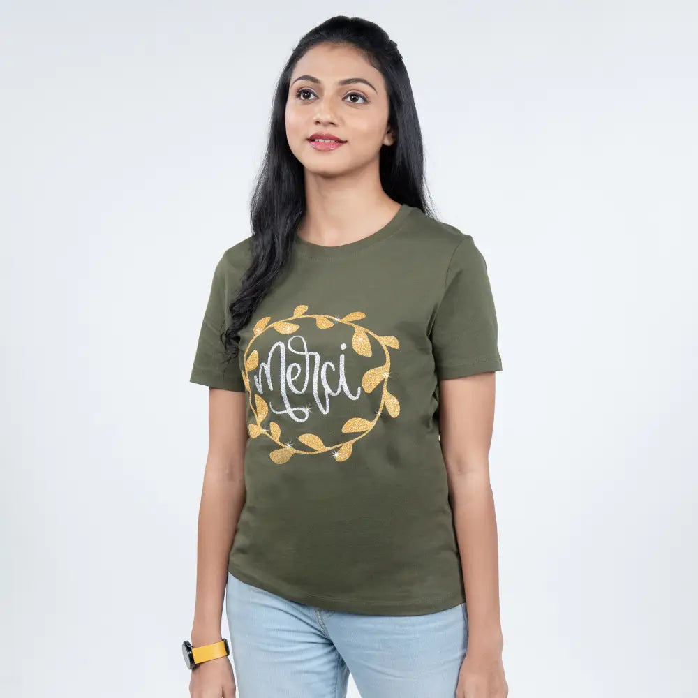 Close-up of olive-green tee highlighting sparkling rhinestone “Merci” lettering