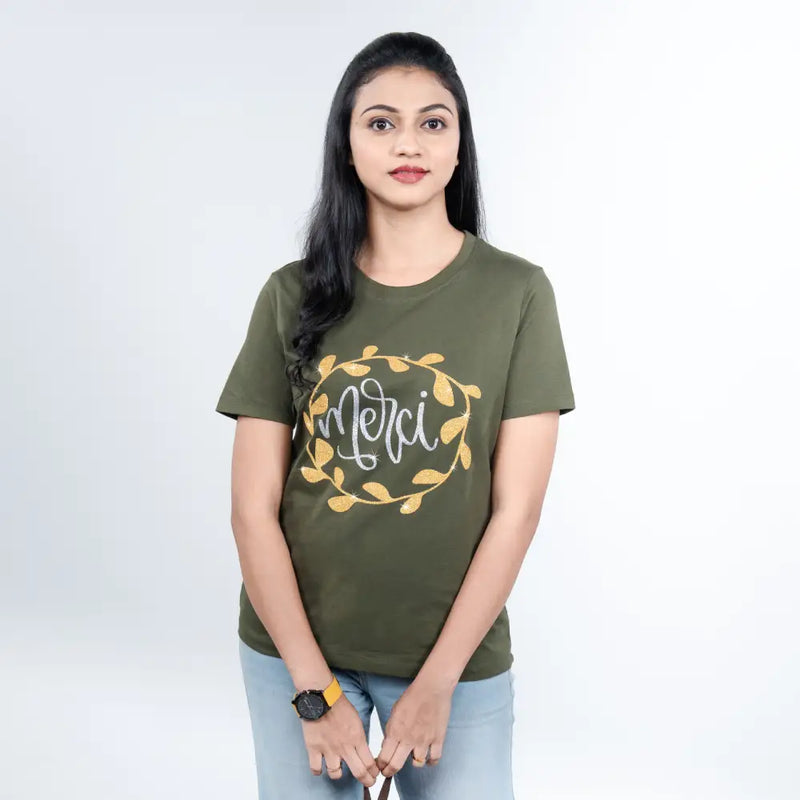 Woman wearing olive-green “Merci” tee paired with chic trousers—elevated casual mood