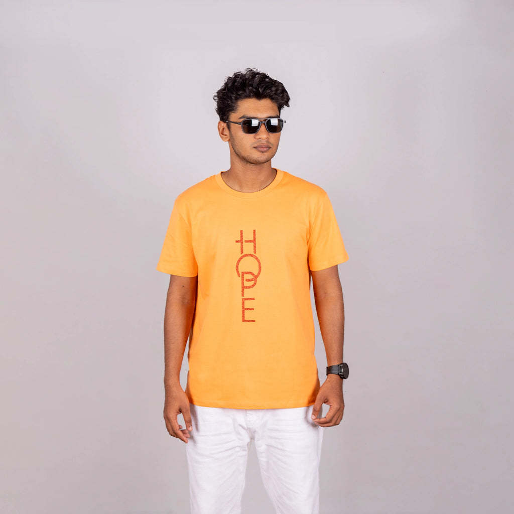 Man wearing sunset orange “HOPE” tee with casual pants—bright optimism meets relaxed style