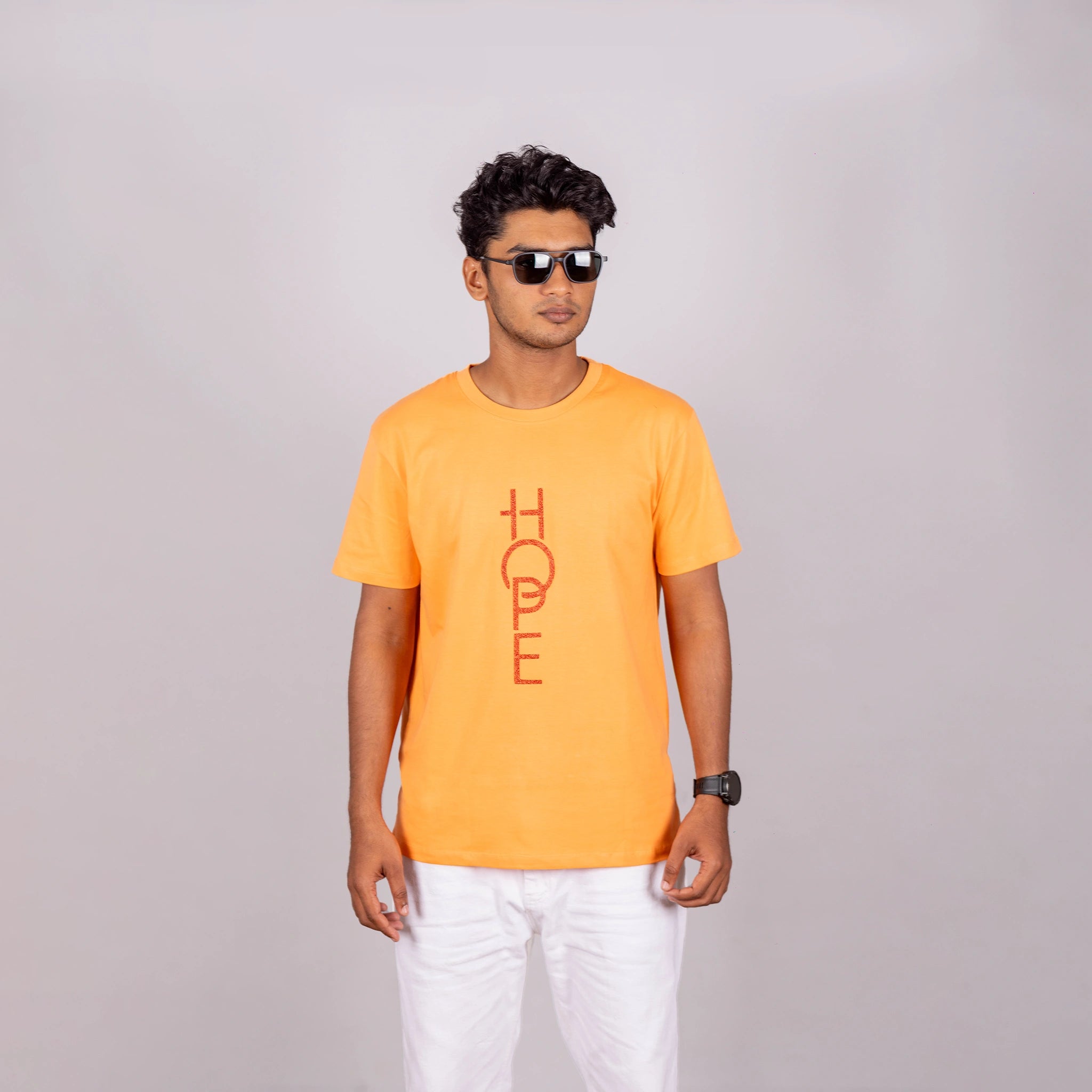 Man wearing sunset orange “HOPE” tee with casual pants—bright optimism meets relaxed style