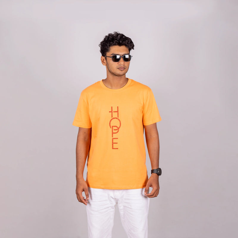 Man wearing sunset orange “HOPE” tee with casual pants—bright optimism meets relaxed style