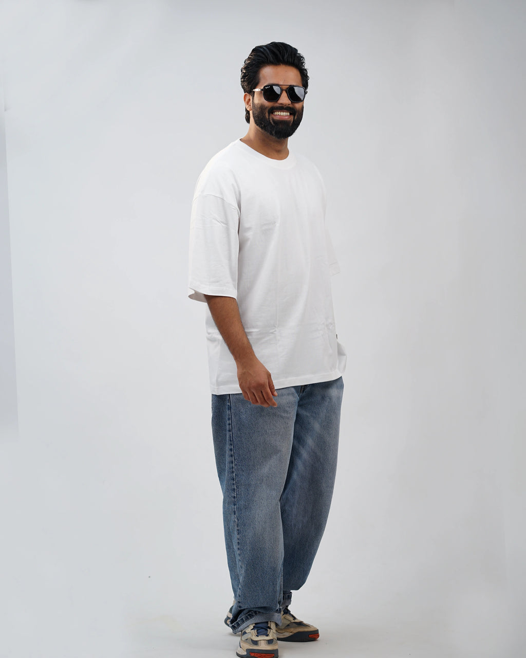 Man wearing oversized white tee outdoors—urban casual with relaxed, stylish ease