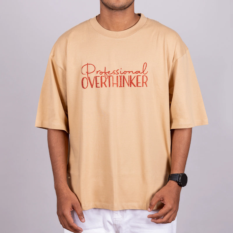 Close-up of glitter-text lettering “Professional Overthinker” on soft cotton tee—detail-focused statement