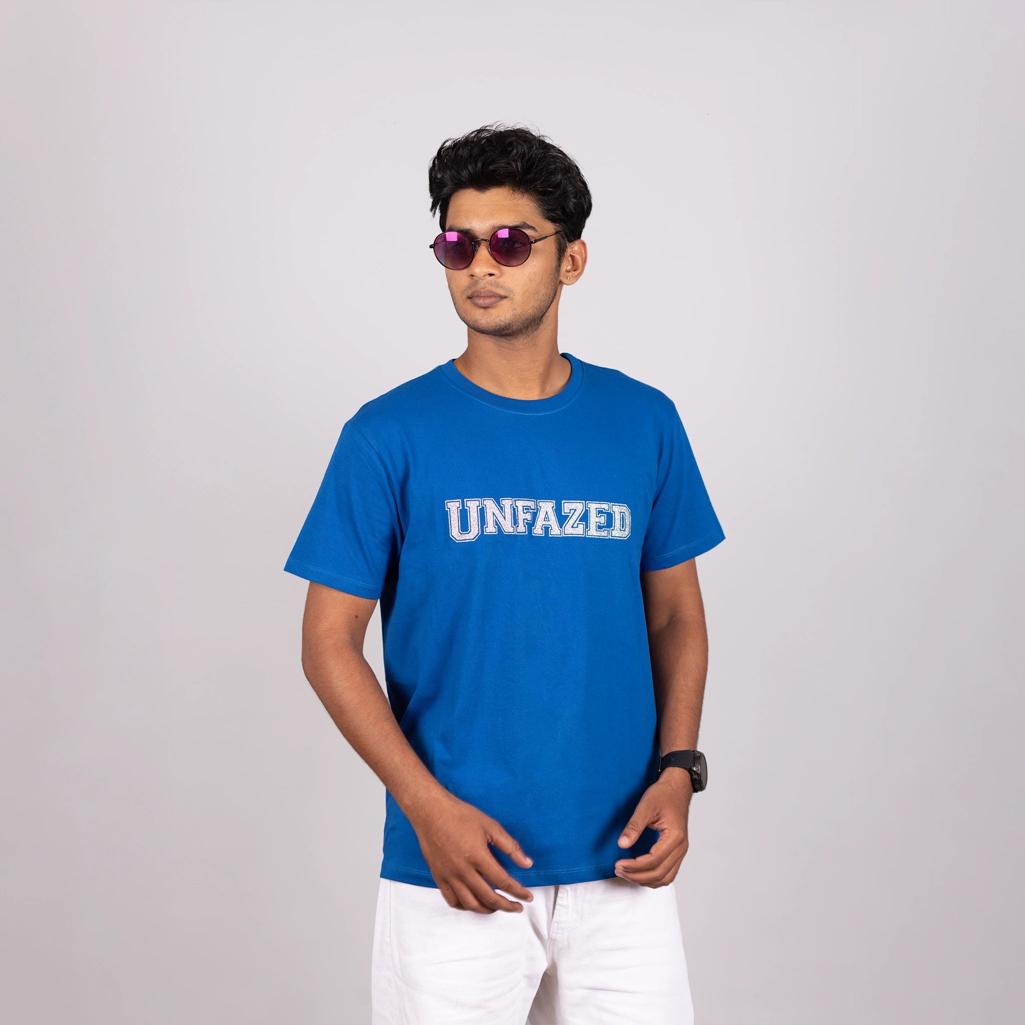 Close-up of glitter “UNFAZED” text on royal blue tee highlighting texture and bold design