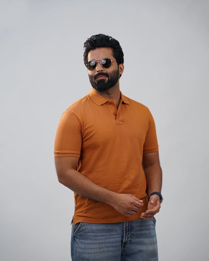 Man outdoors wearing terracotta polo t-shirt for men in India, smart casual styling with denim.