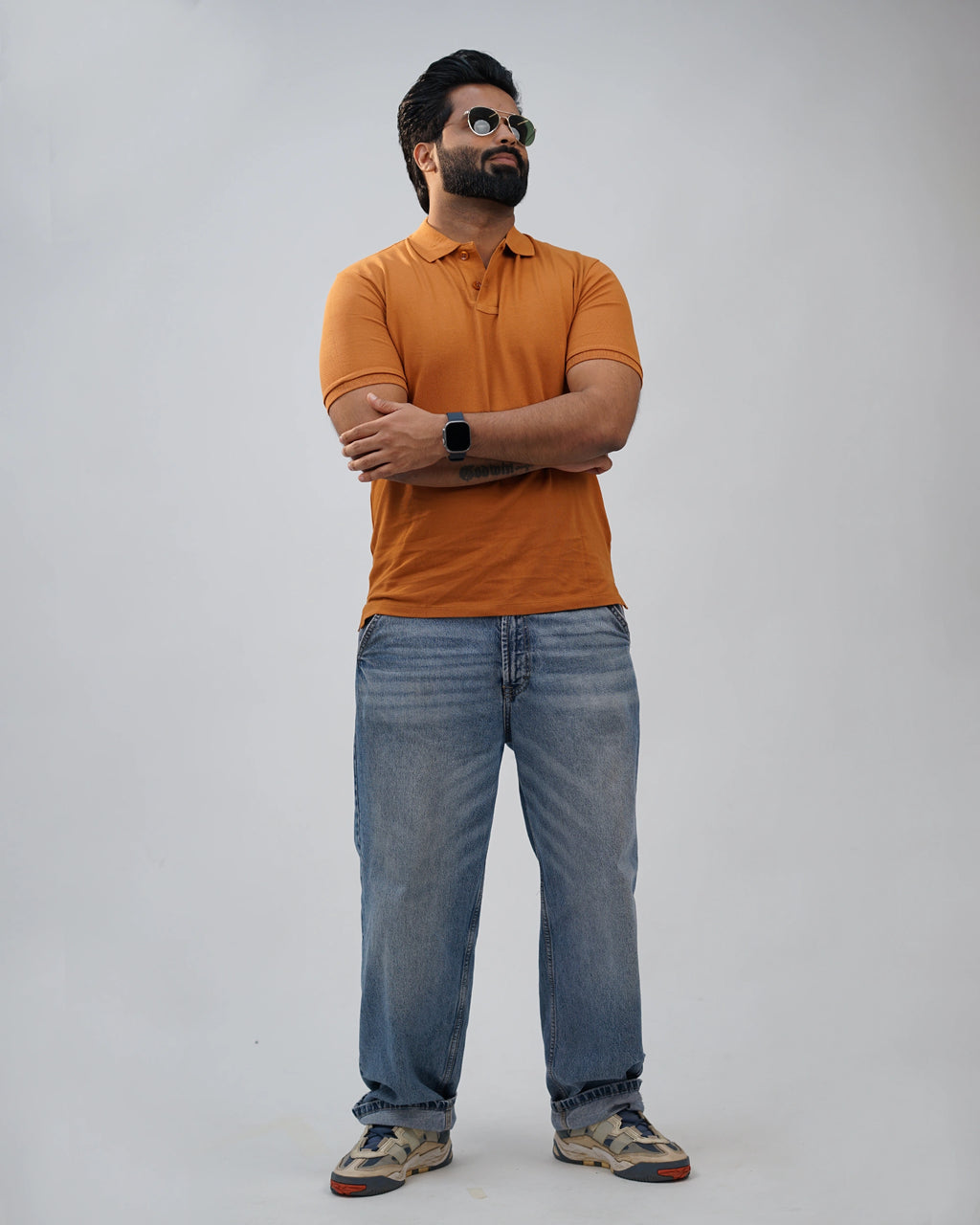 Terracotta polo t-shirt for men, casual side pose with sunglasses and jeans.