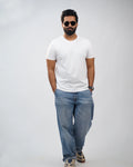 Man wearing classic white crew-neck tee for men, front view, styled with blue jeans